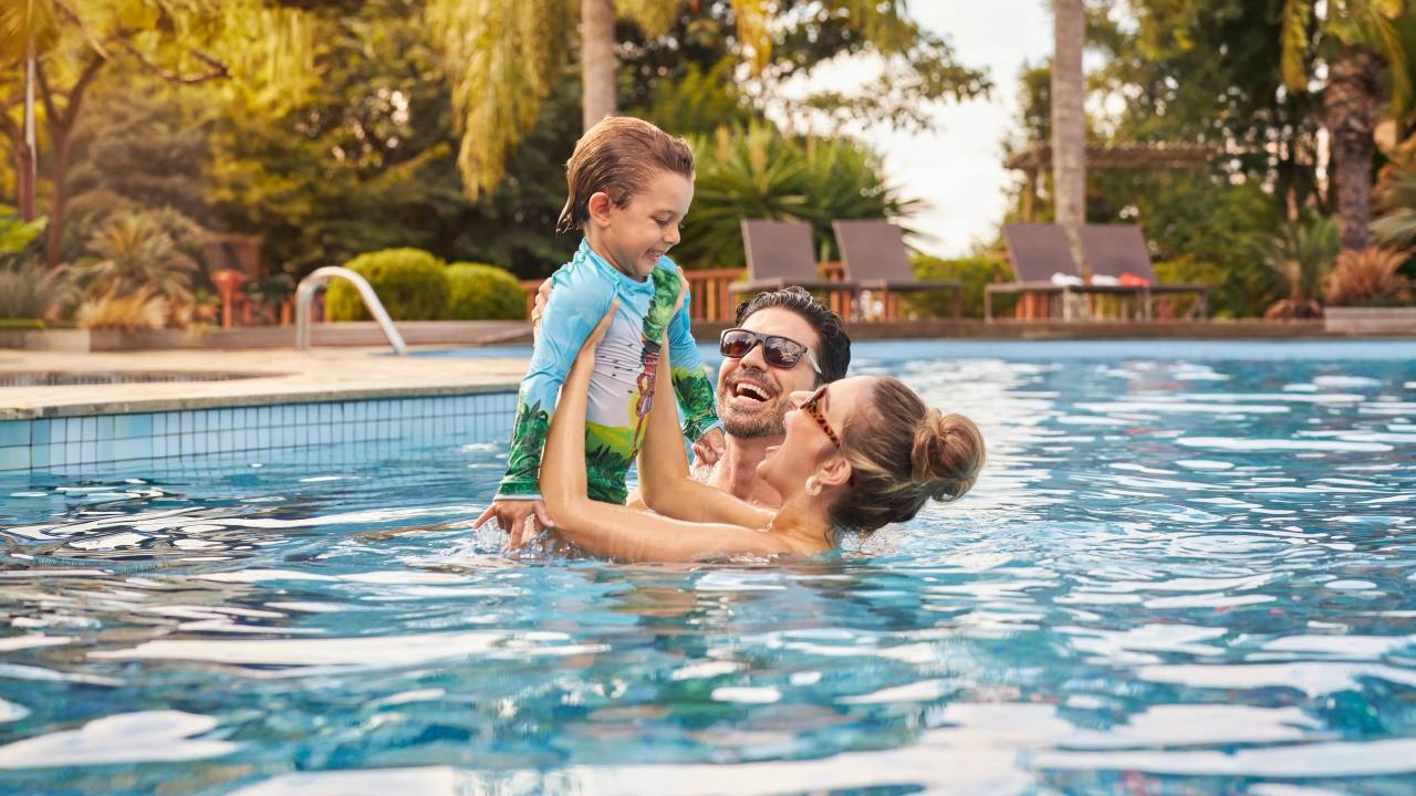 casal na piscina segurando criança no colo